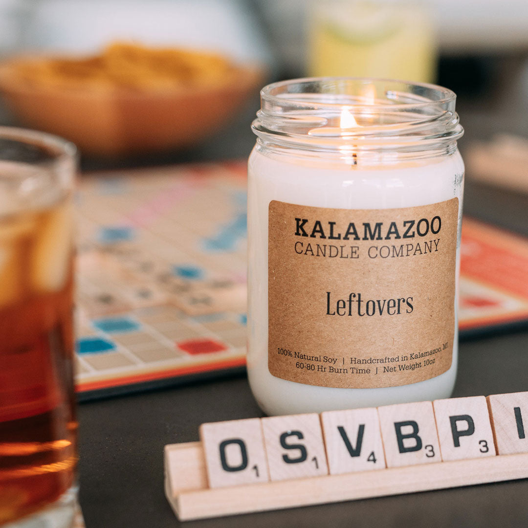 A game of scrabble being played with a leftovers candle