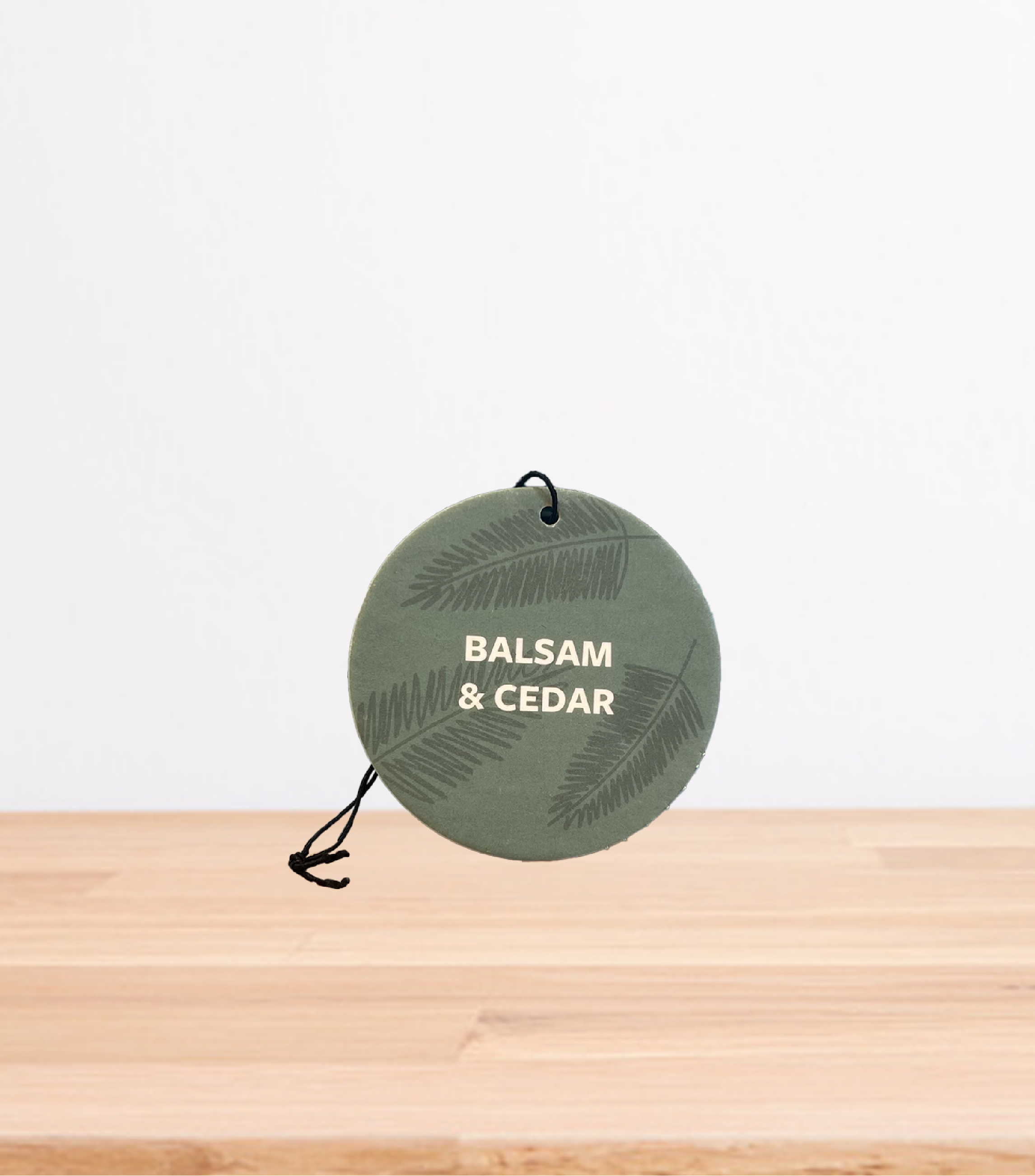 A Balsam &amp; Cedar Car Freshener on a wooden table.