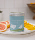 A Large blue candle tin with laundry blowing in the breeze on the side. Made in Kalamazoo, MI USA. Scented with Citrus, Fresh Laundry, and Earth.