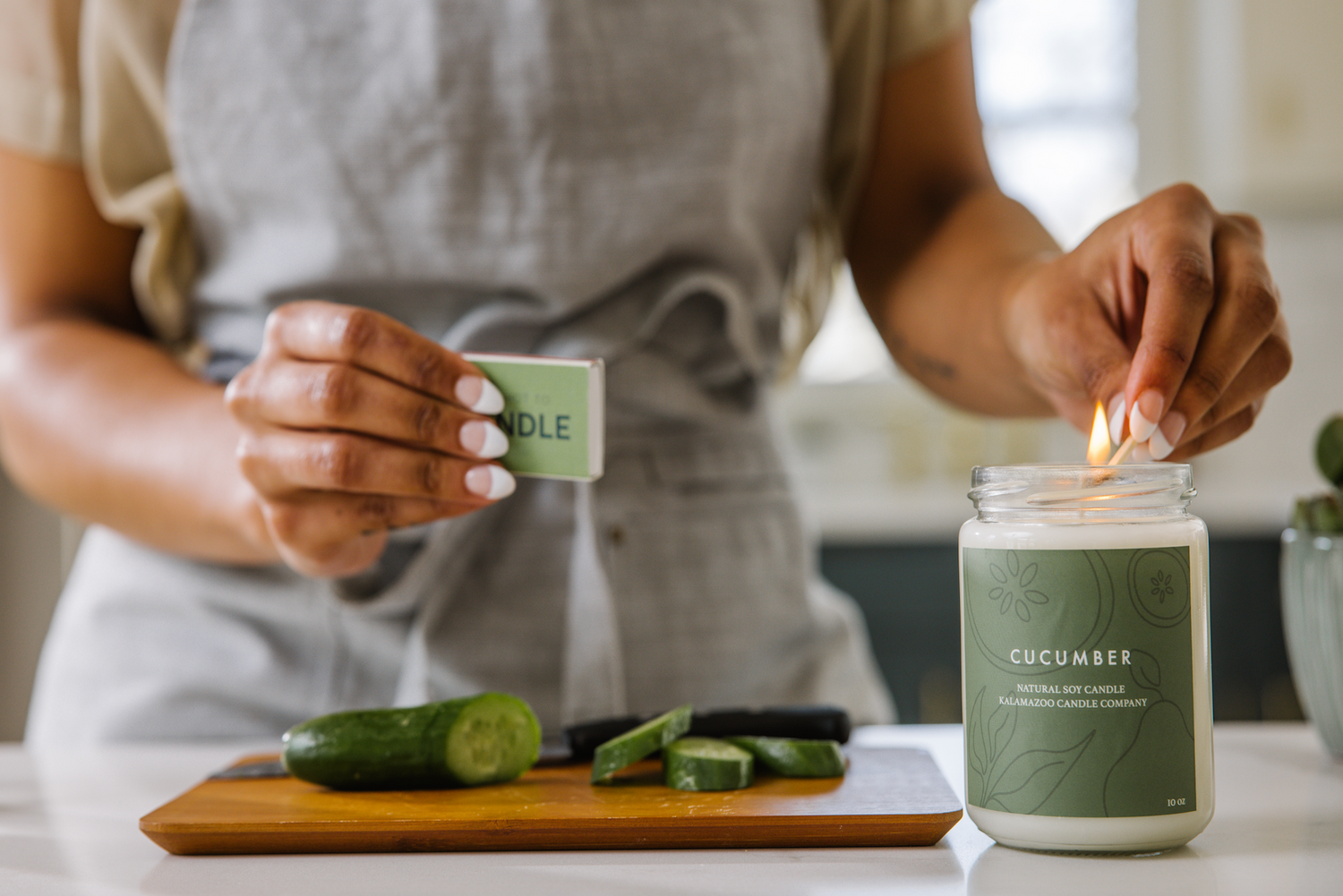 Hand lighting a cucumber candle with a match.