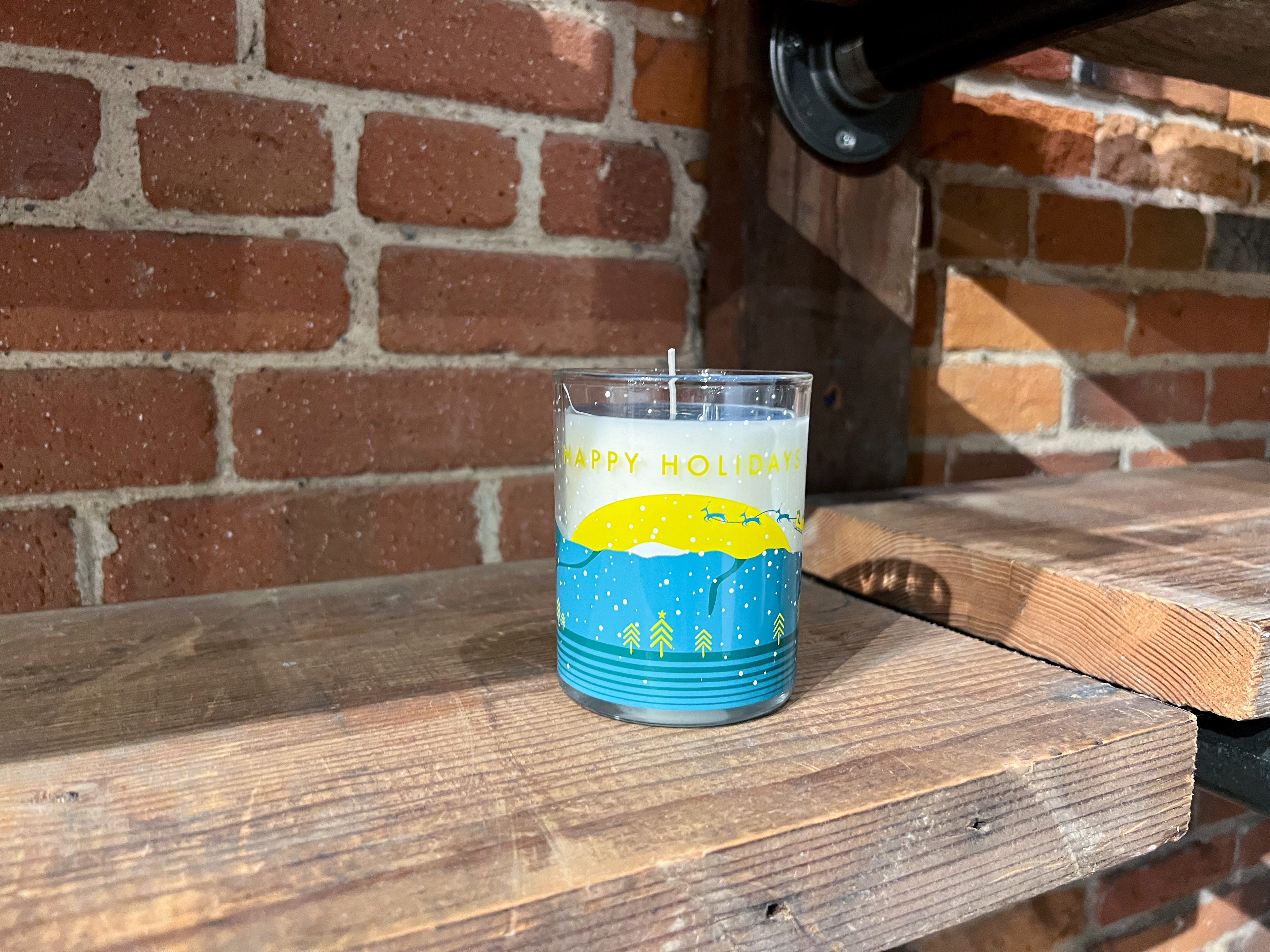 The 2023 Holiday Jar sitting on a wooden shelf in front of a brick wall