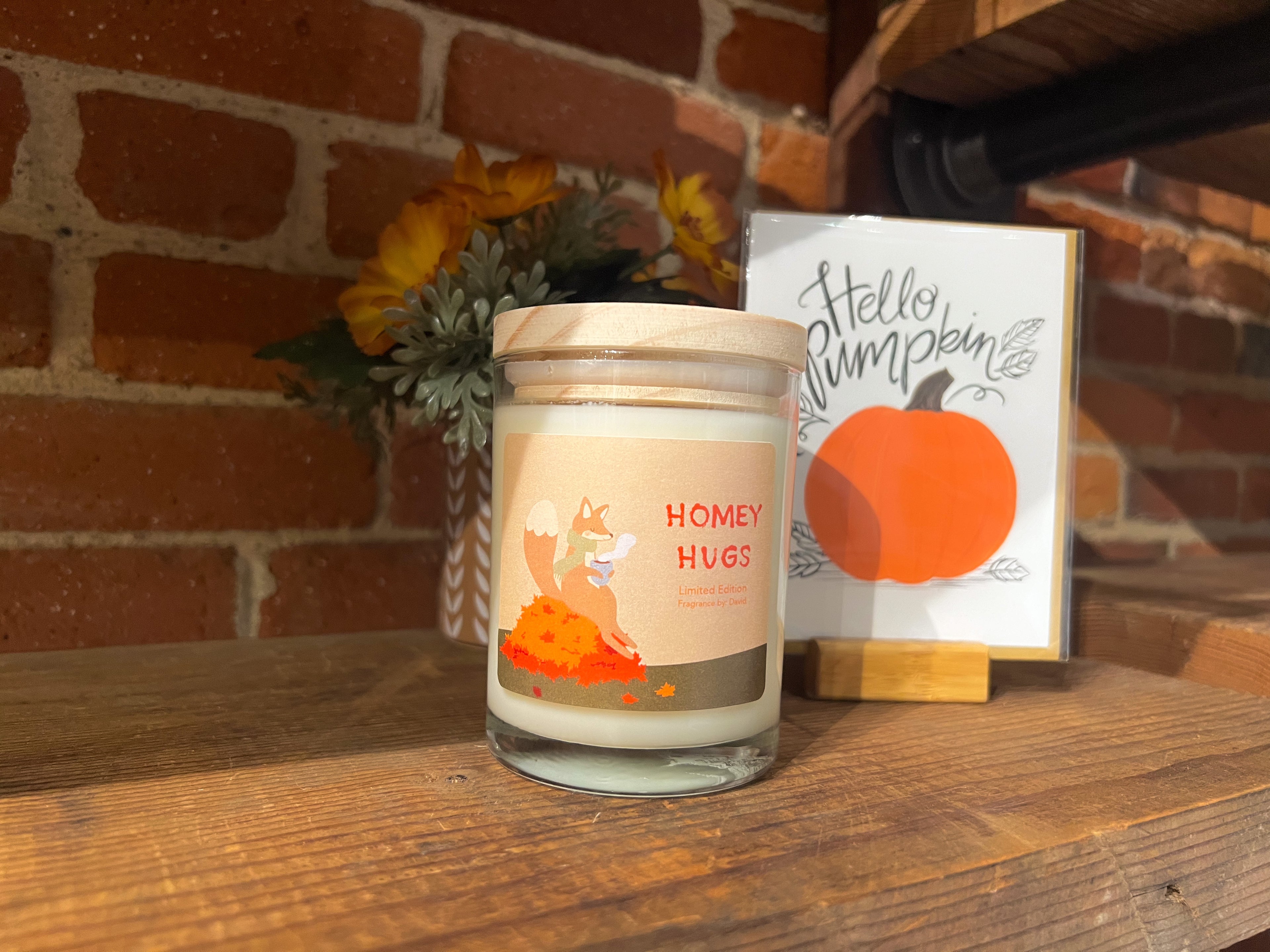 A Homey Hugs Candle Jar on a wooden ledge