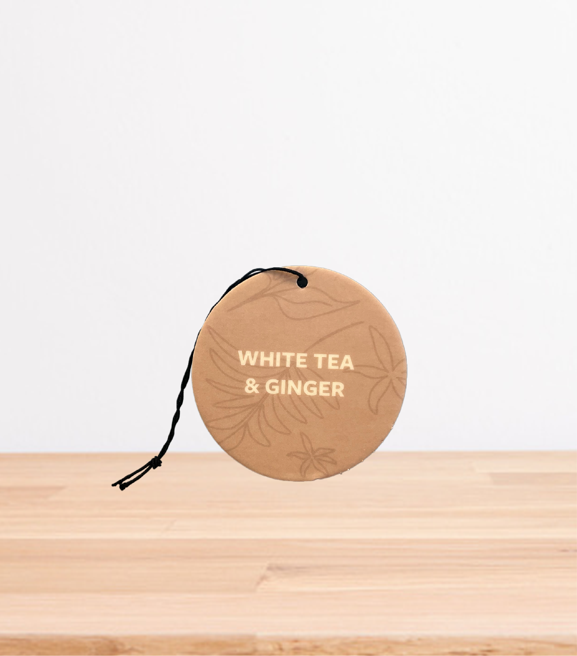 A White Tea & Ginger Car Freshener on a wooden table.
