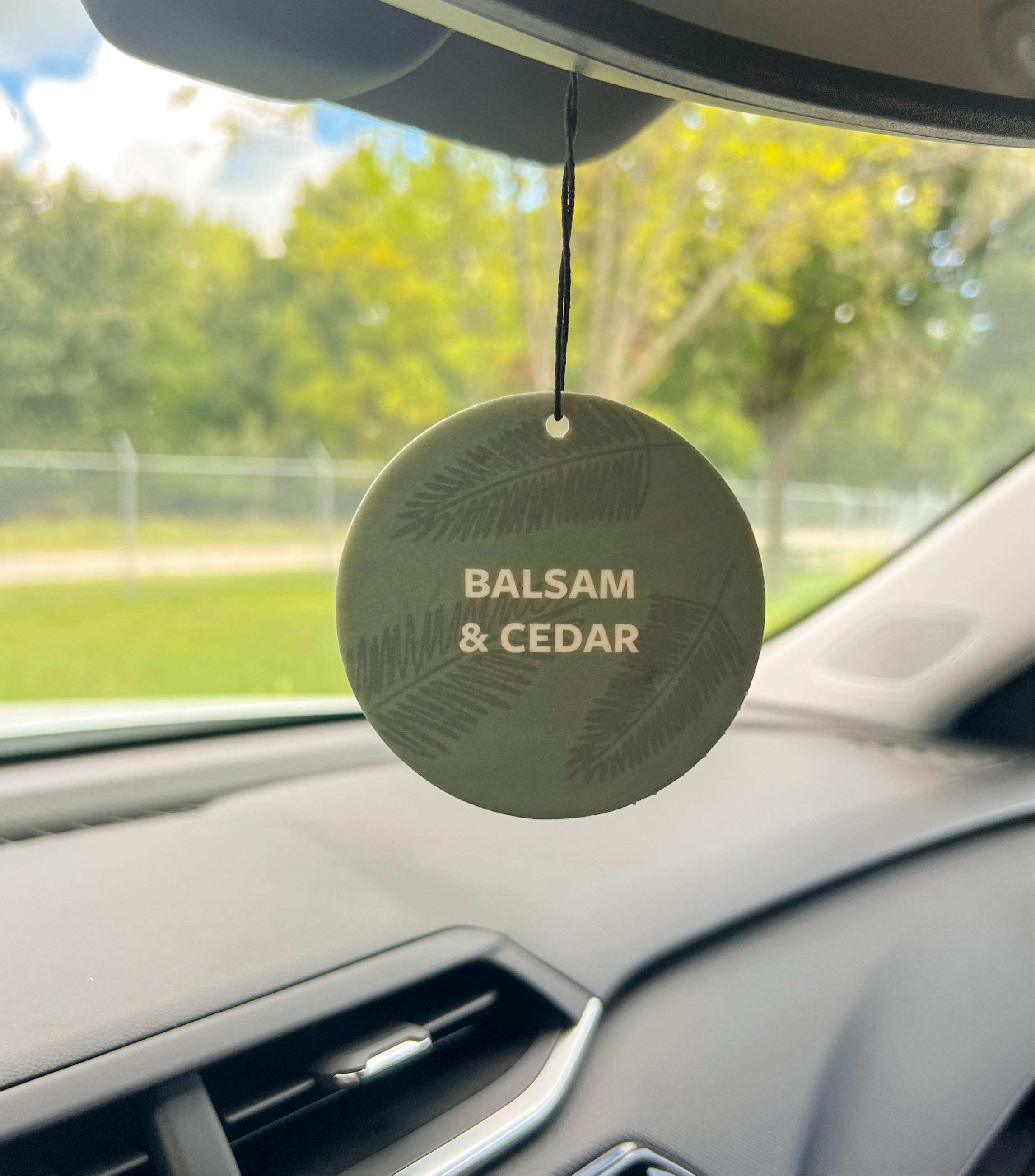A Balsam & Cedar Car Freshener Hanging in a car.