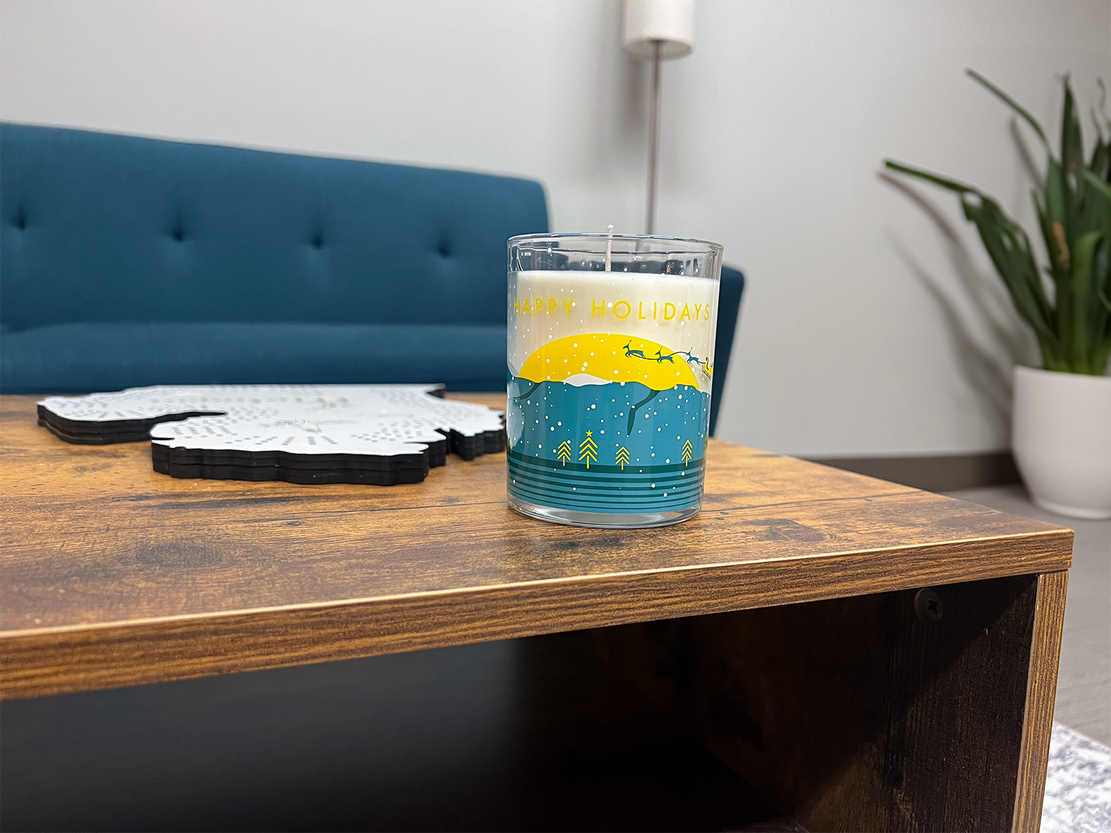 The 2023 Holiday Jar sitting on a wooden table in front of a cribbage board and blue couch.