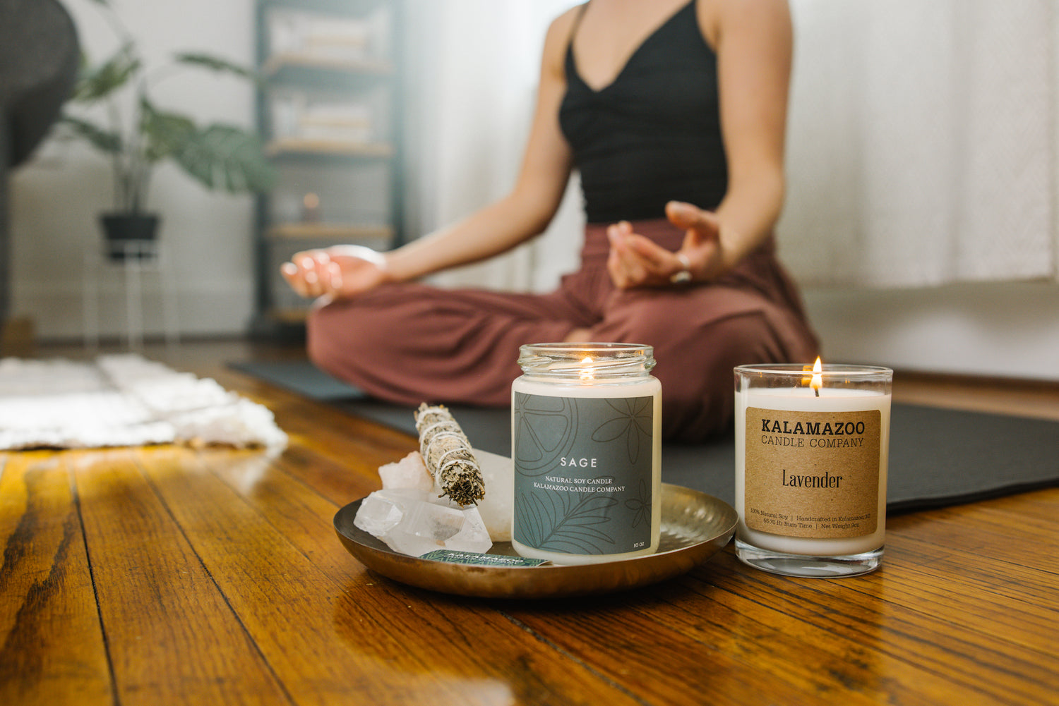 person doing yoga next to a sage and lavender candle