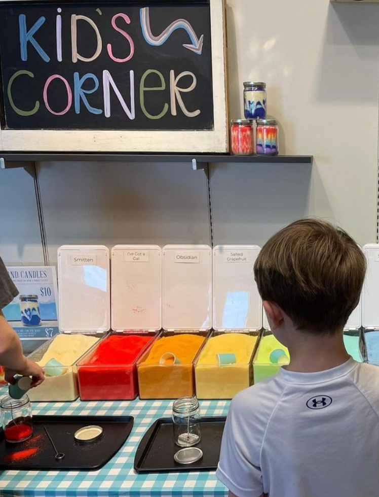 A child looking at buckets of sand wax