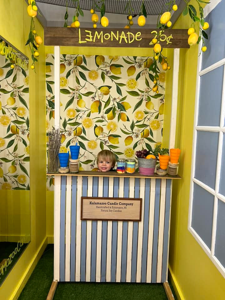 A child standing behind a lemonade stand