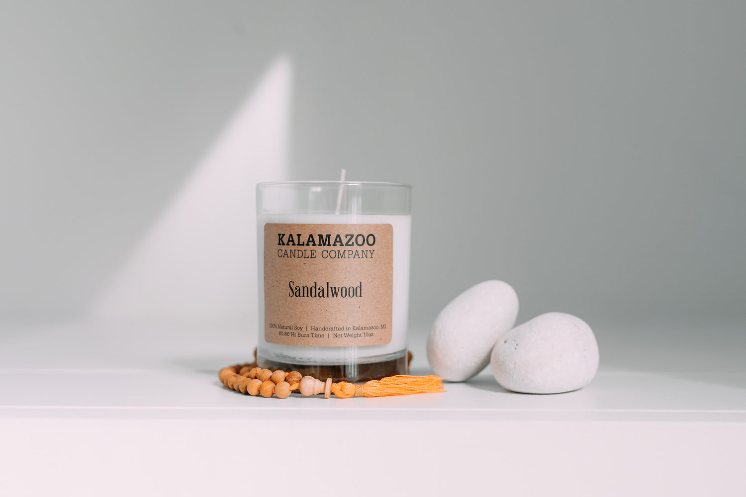 A Sandalwood candle next to some stones and beads
