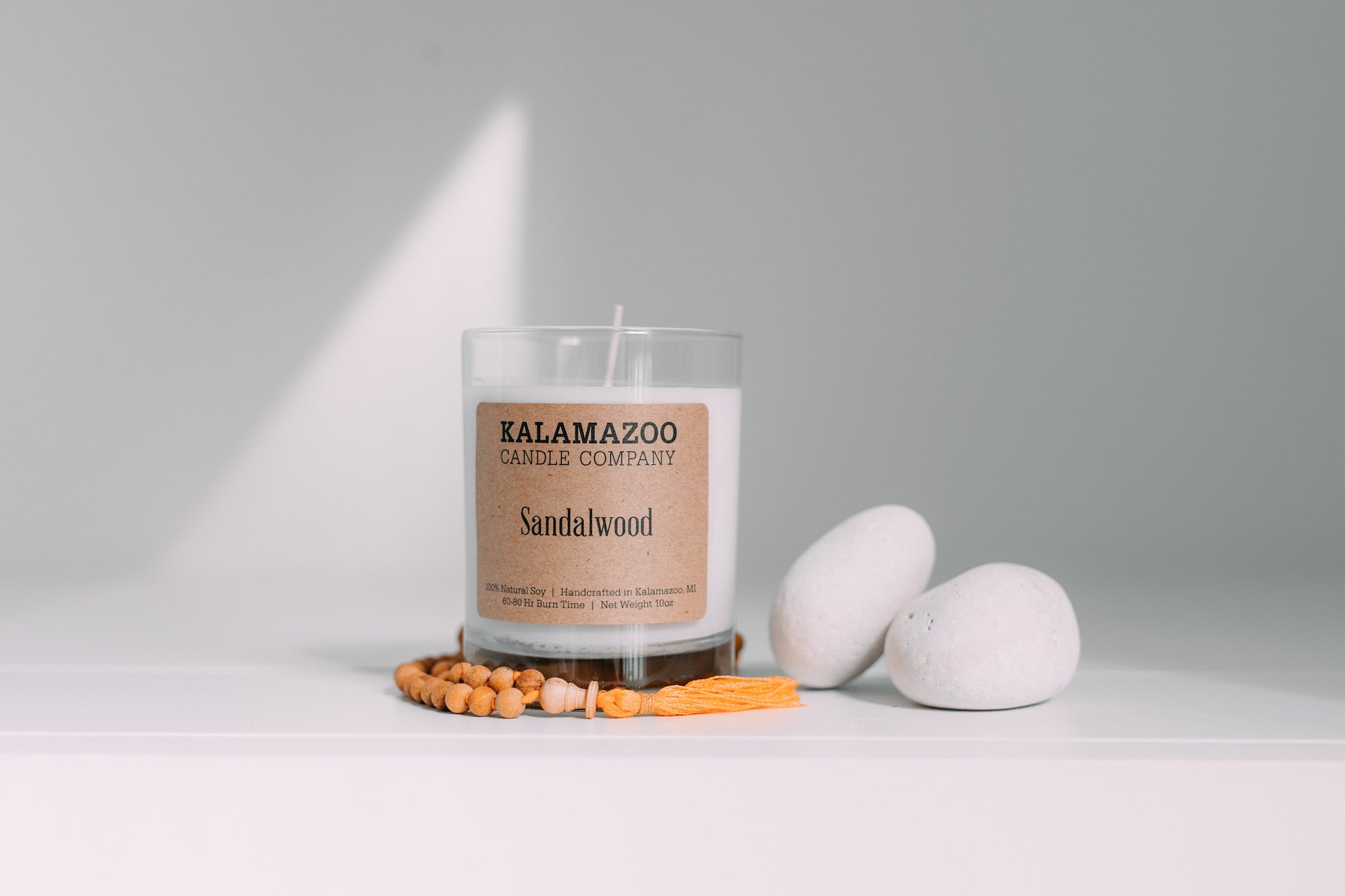 A Sandalwood candle next to some stones and beads