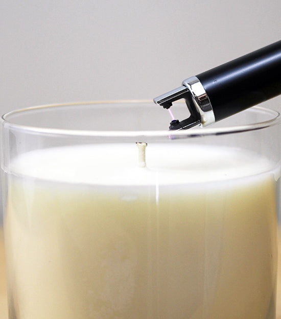 An electric lighter lighting a candle.