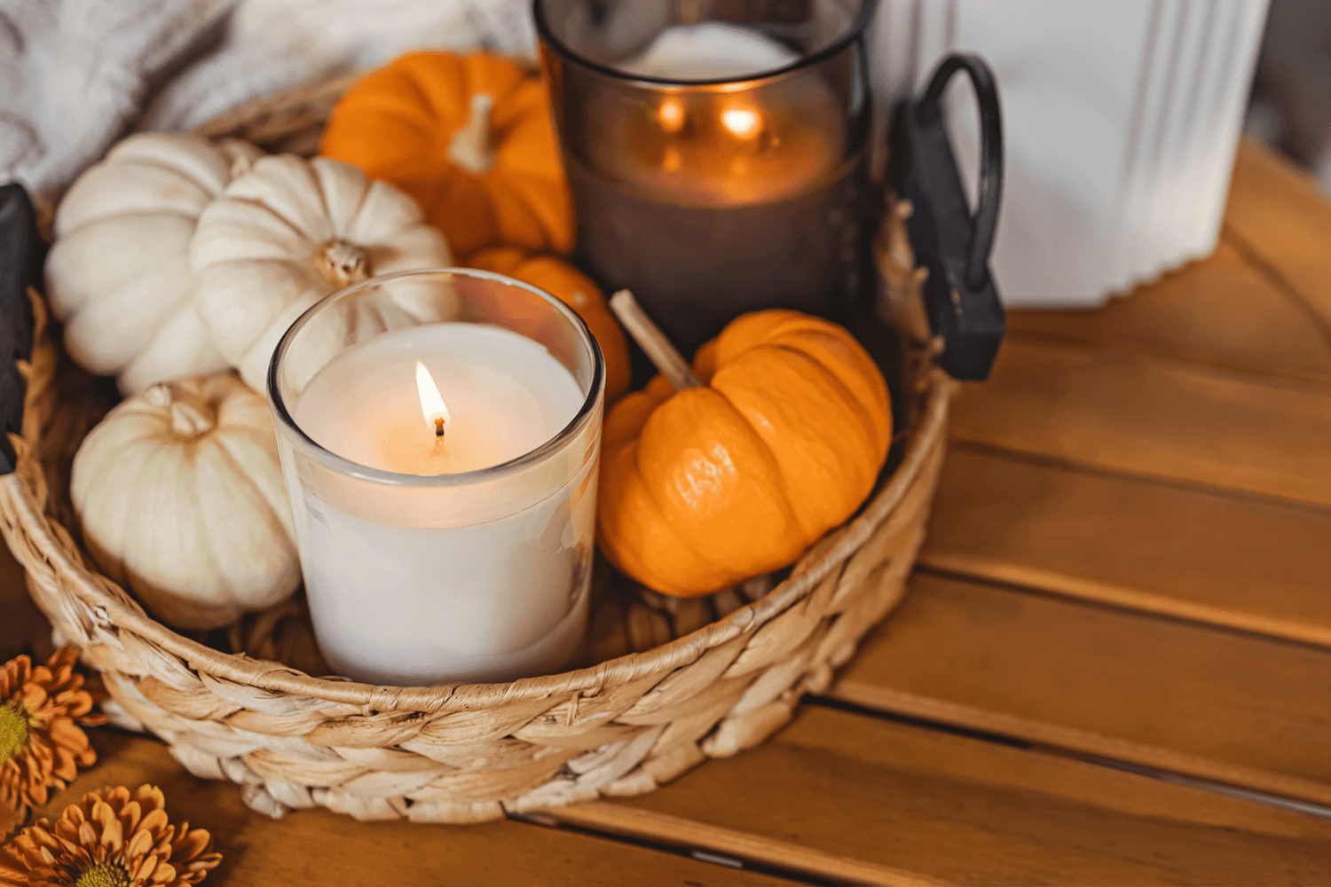 A Candle burning in a basket with pumpkins