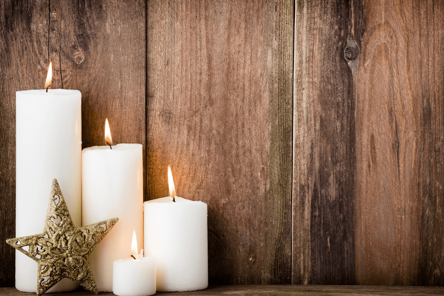 4 Candles burning in front of a wooden wall