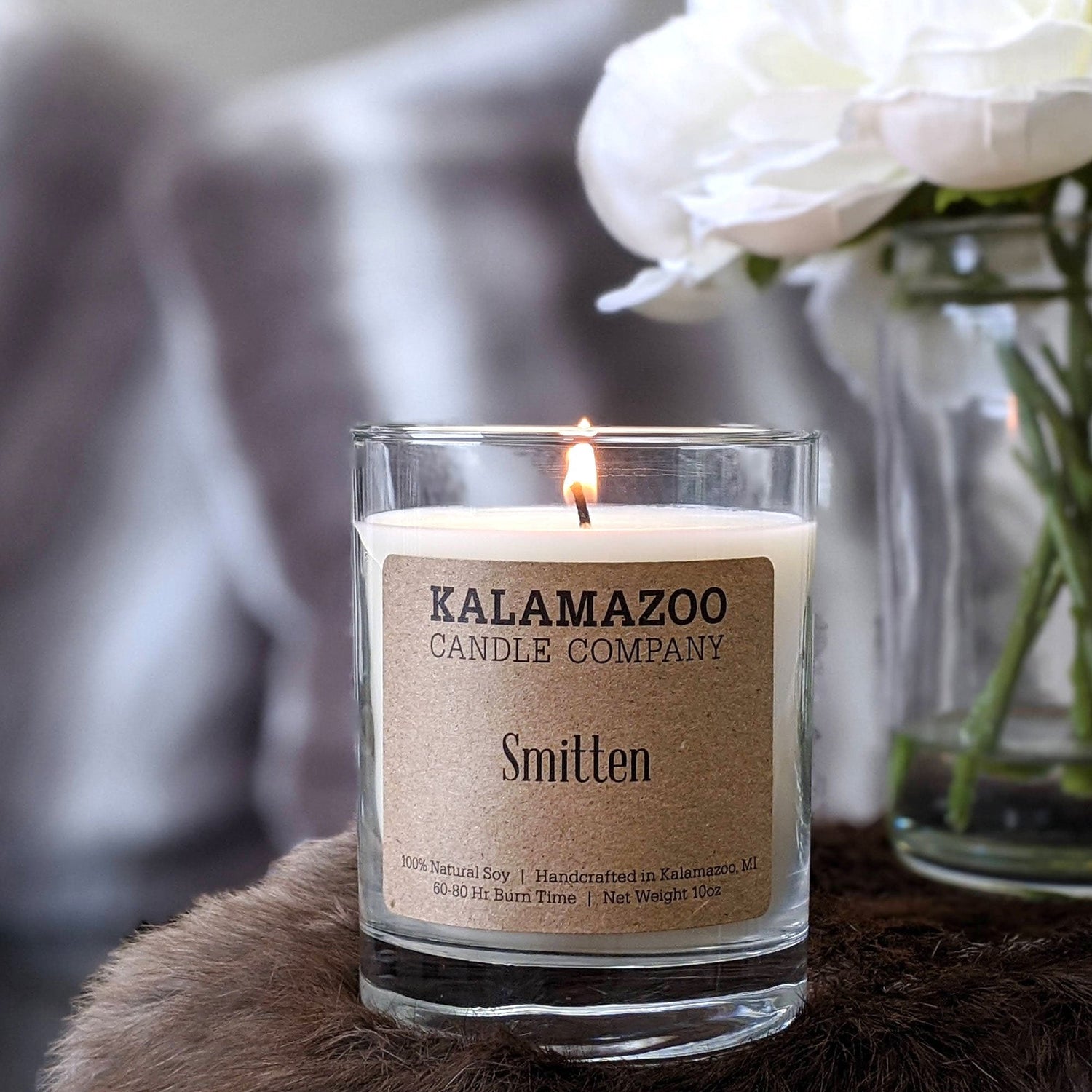 A Smitten Candle next to White Roses