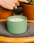 A Dark Green 3-Wick Ceramic candle scented like Clover Leaf & Aloe.