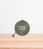 A Balsam & Cedar Car Freshener on a wooden table.
