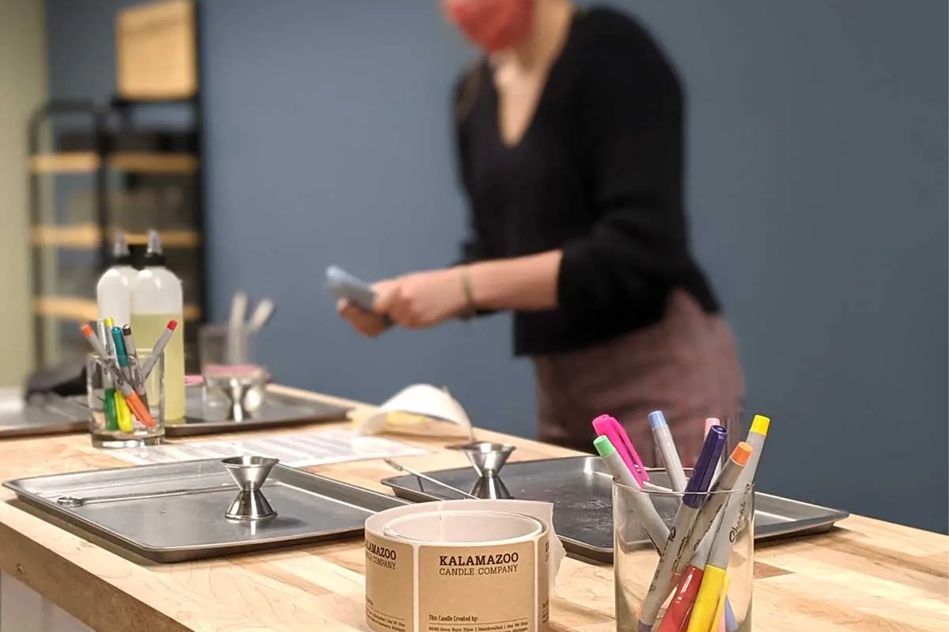A table with candle making supplies and labels.