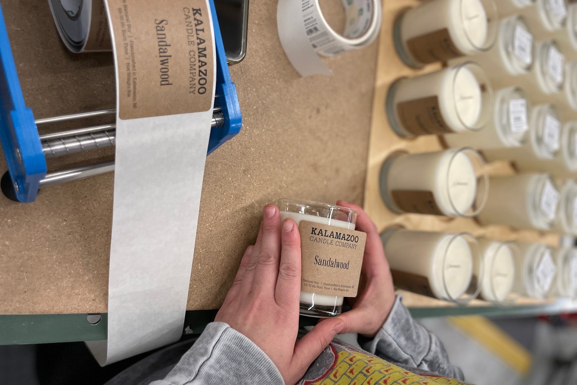 Hands labeling a sandalwood candle