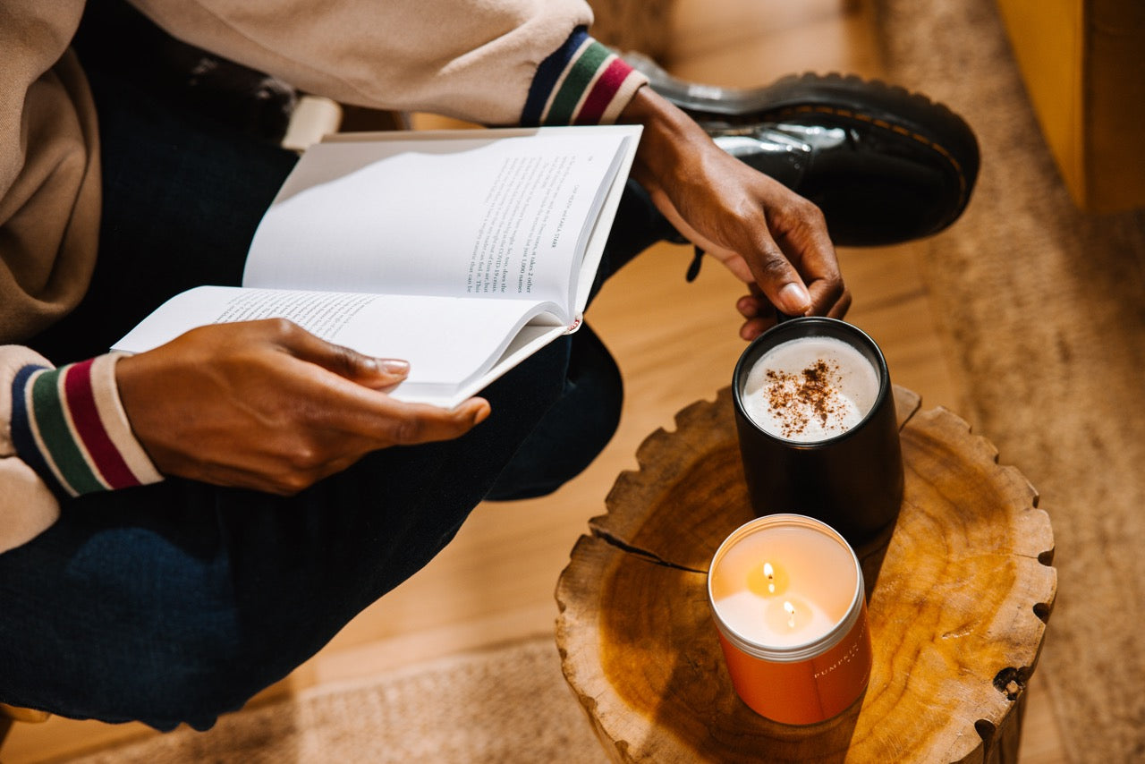 A Pumpkin Spice Candle next to a coffee and a book