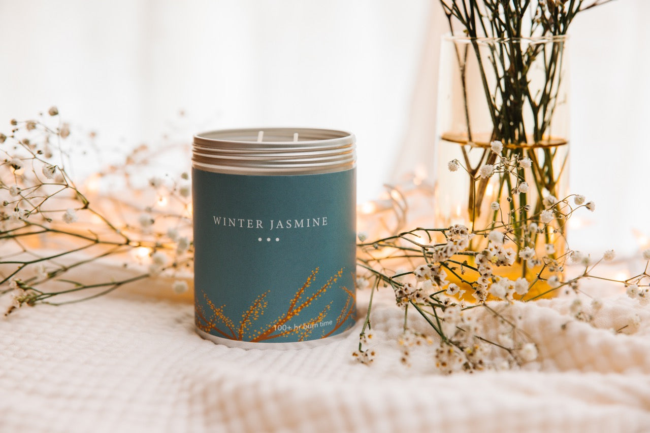 A Large 2-Wick Winter Jasmine Candle Surrounded by Jasmine.