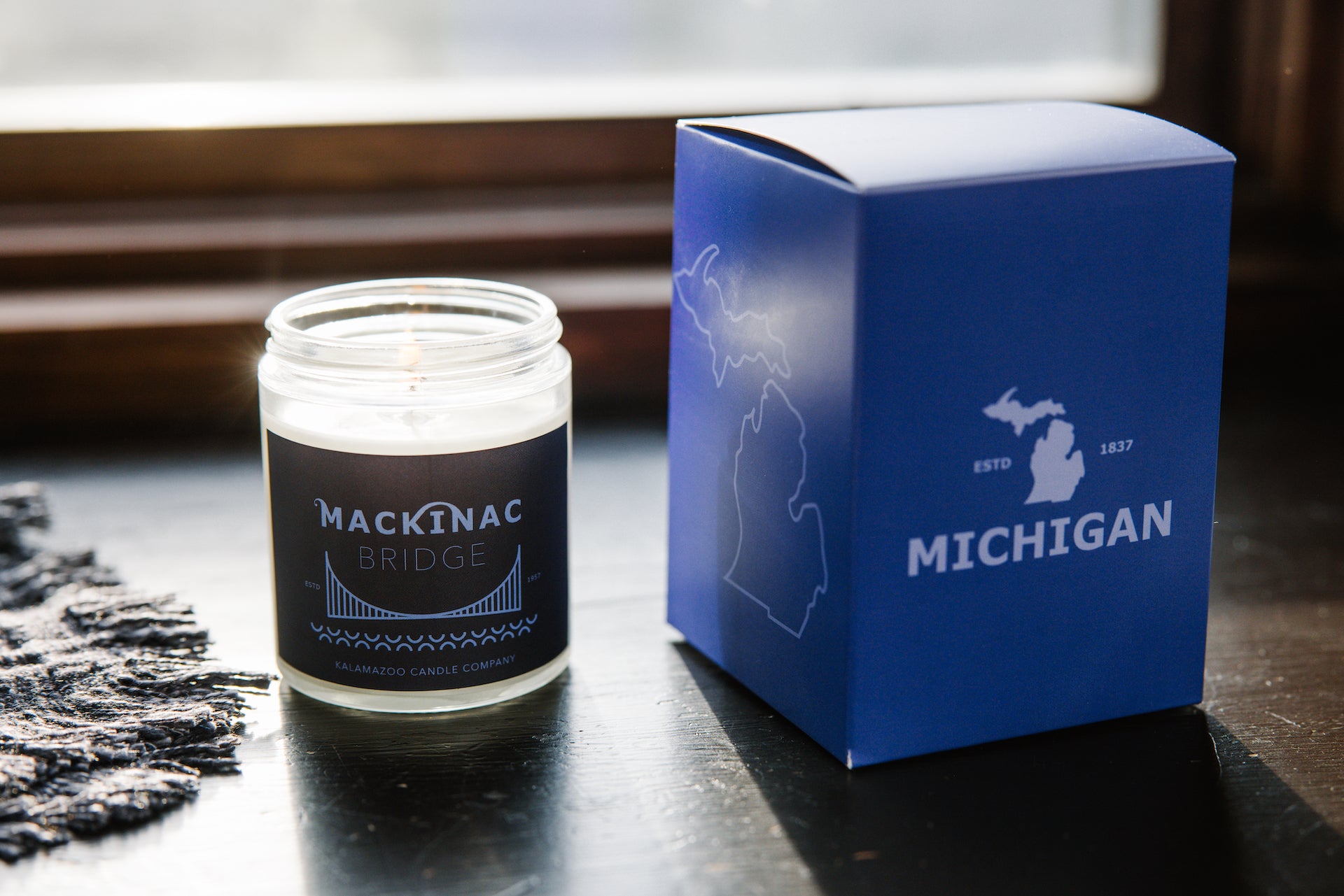 Mackinac bridge candle next to gift box.