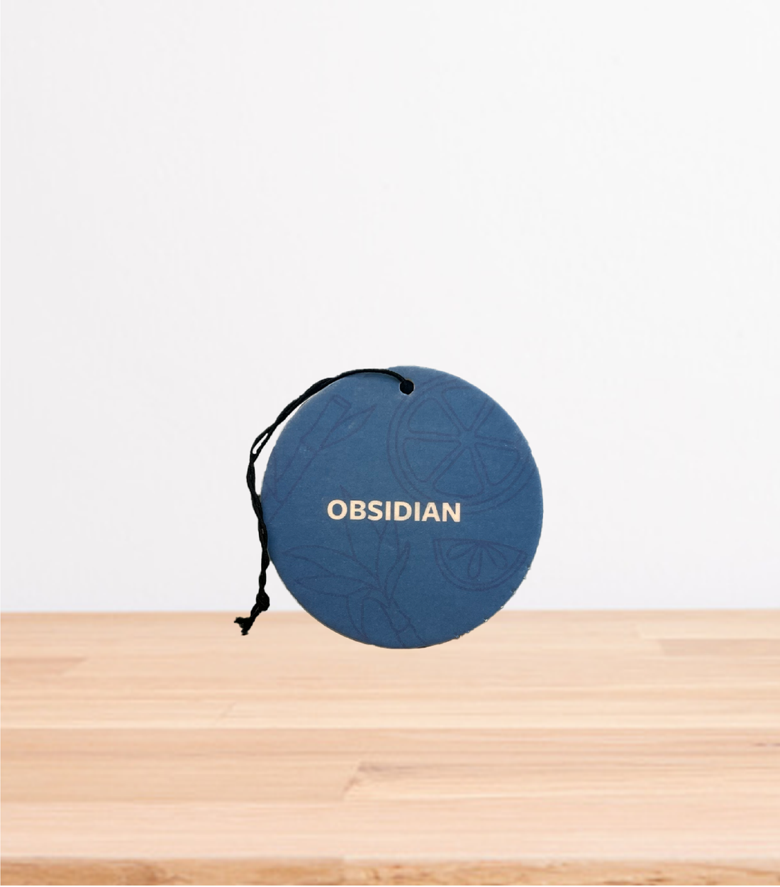 An Obsidian Car Freshener on a wooden table.