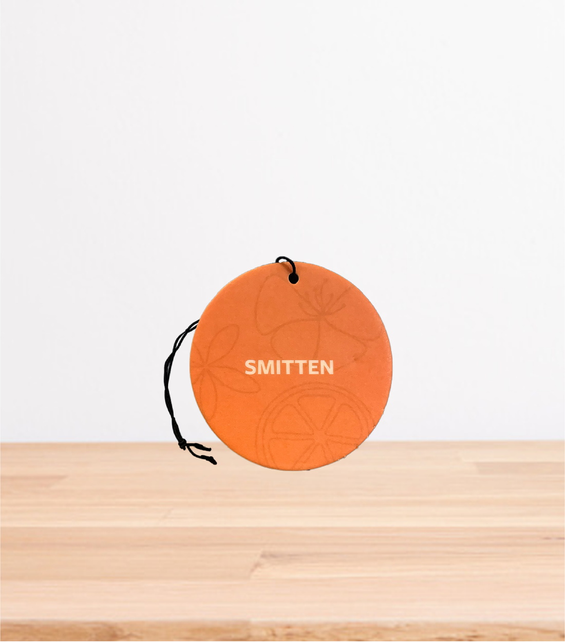 A Smitten Car Freshener On a wooden Table.
