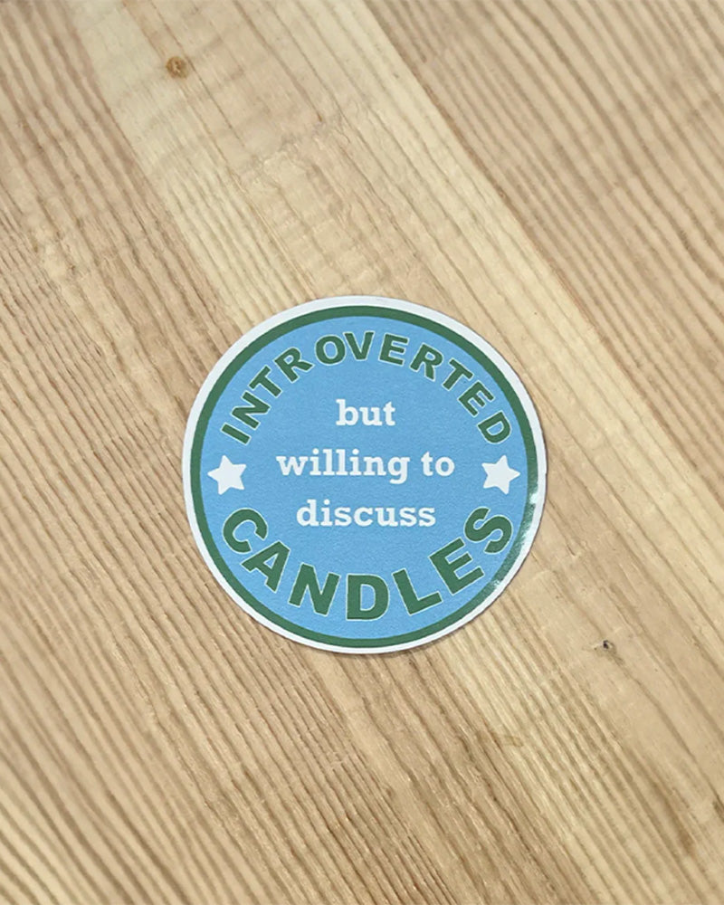 A Blue circular sticker that says &quot;Introverted but willing to discuss candles&quot;.