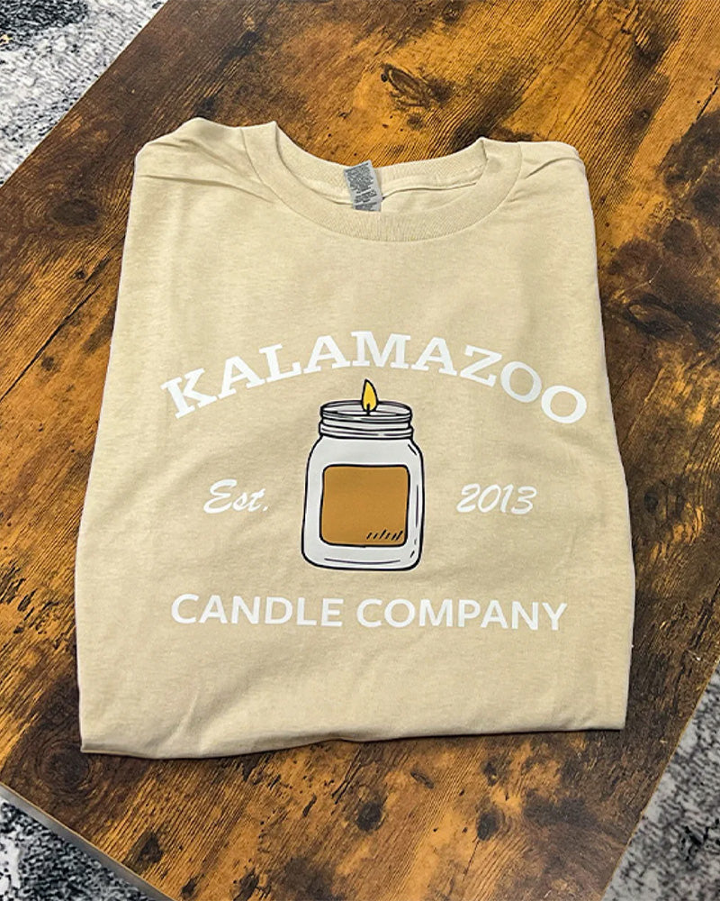 A tan Kalamazoo Candle T-Shirt with a candle on the front.