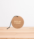 A White Tea & Ginger Car Freshener on a wooden table.