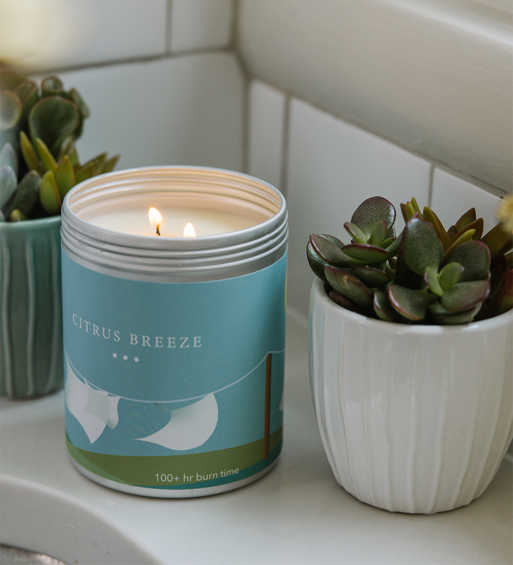 A Citrus Breeze candle by a sink with a plant