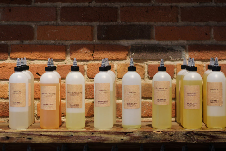 Row of fragrance oil bottles on a wood shelf at the Kalamazoo Candle candle-making bar