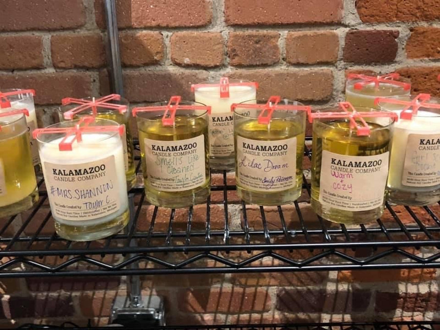 Guest-made soy candles with handwritten labels cooling on a rack at the candle bar