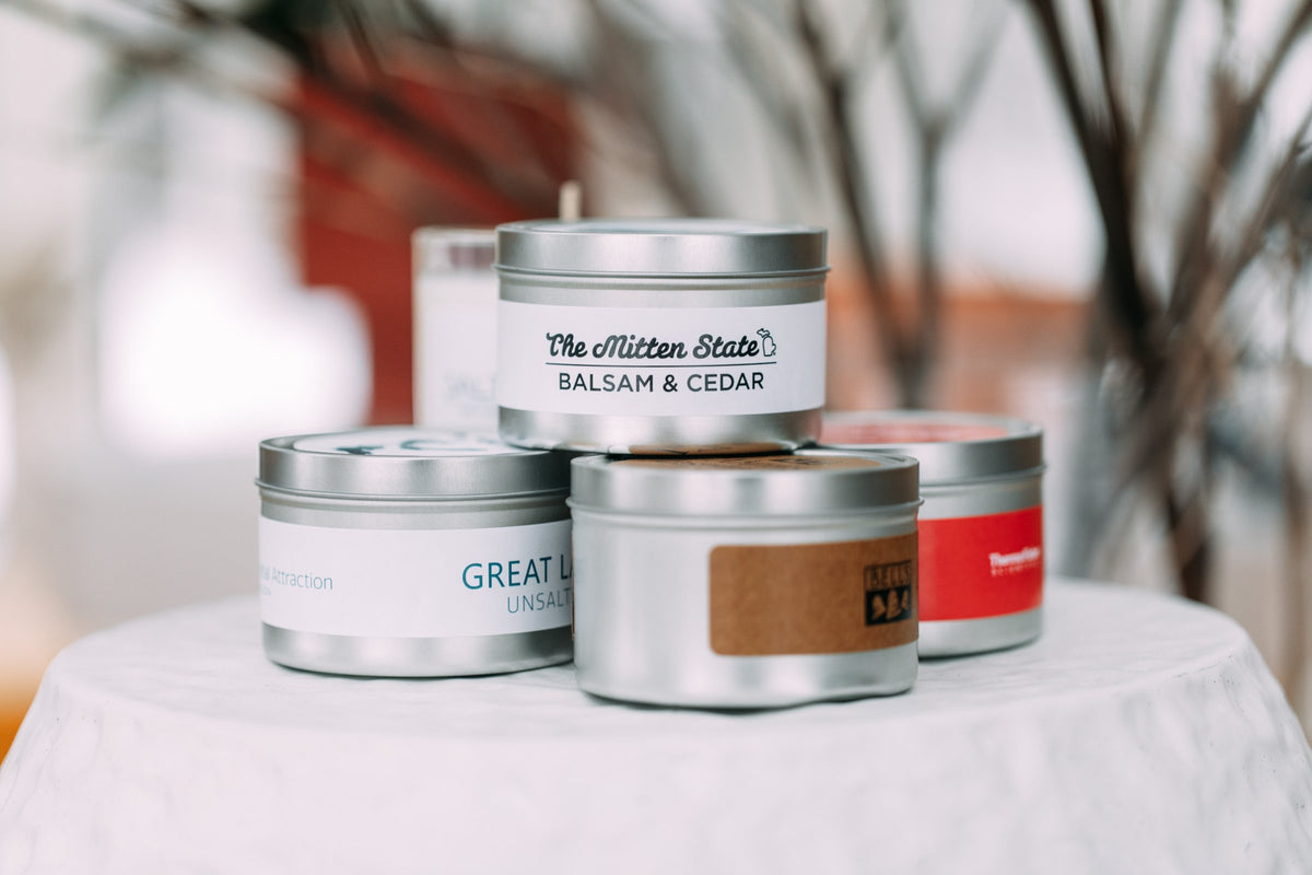 Custom label soy candle tins stacked on a white tablecloth