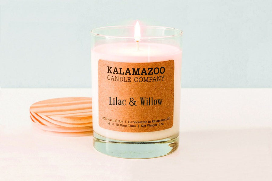 Lit Lilac & Willow soy candle in a glass jar with a wooden lid