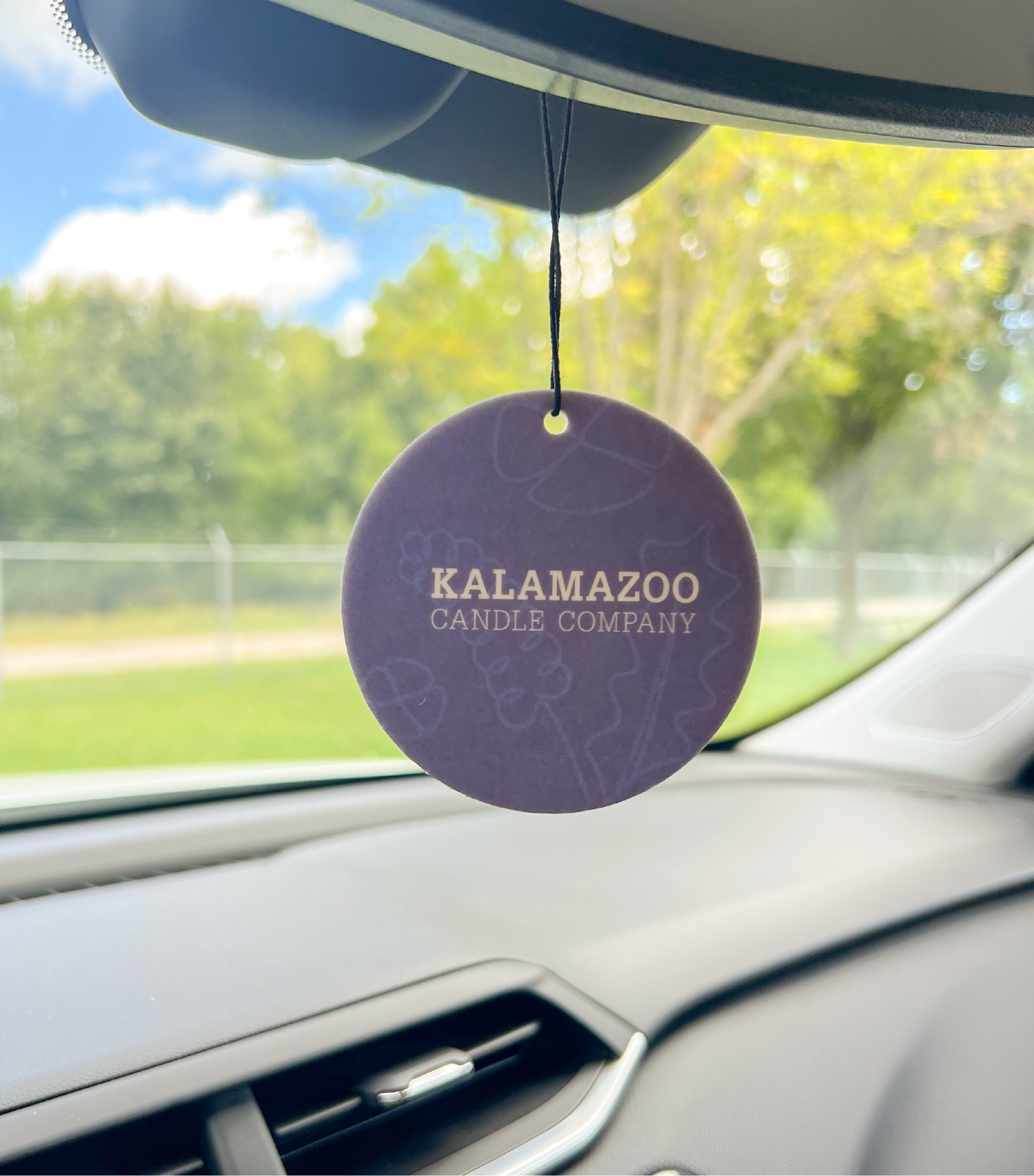 The back of a lavender car freshener hanging in a car.