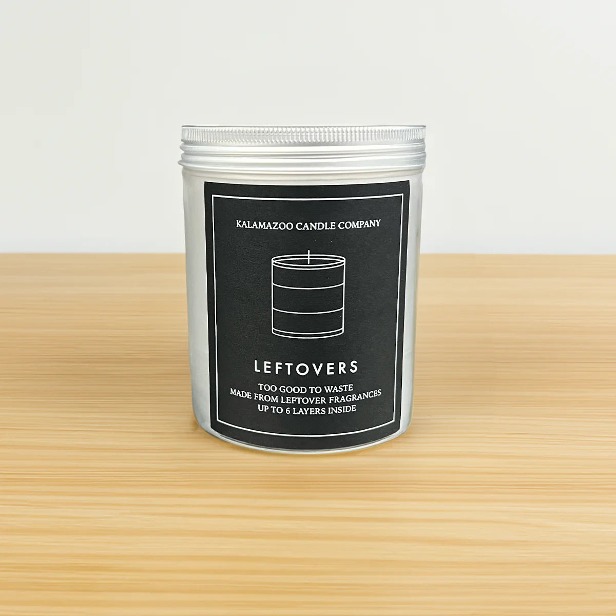 Metal tin jar with a screw top lid with a black label with the words Kalamazoo Candle Company in the scent Leftovers with small descriptors that say &quot;too good to waste, Made from Leftover Fragrances, Up to 6 layers inside&quot;