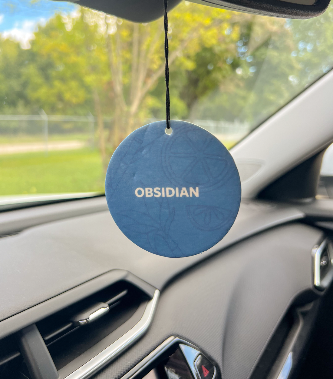 An Obsidian Car Freshener hanging in a car.