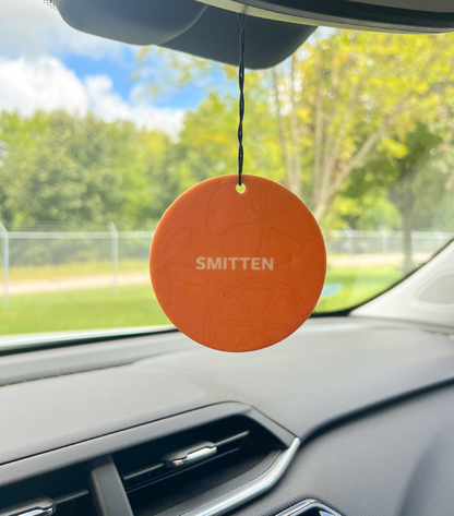 A Smitten car freshener hanging in a car.