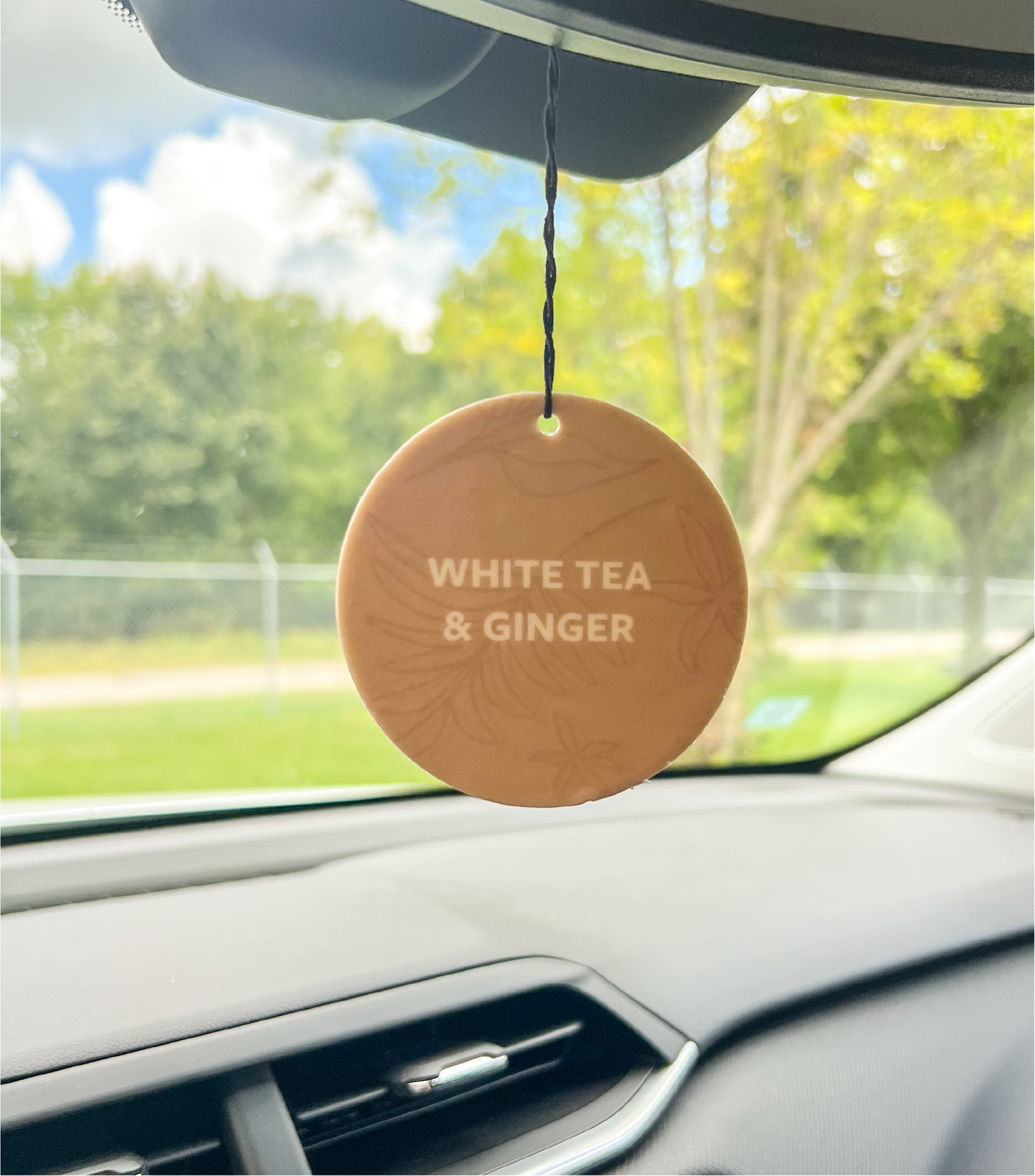 A White Tea &amp; Ginger Car Freshener Hanging in a car.