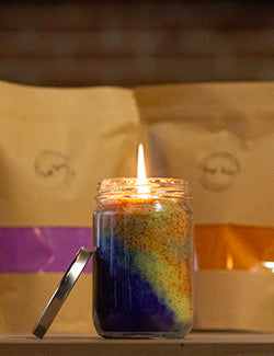 A Sand Candle burning in front of two bags of sand wax.